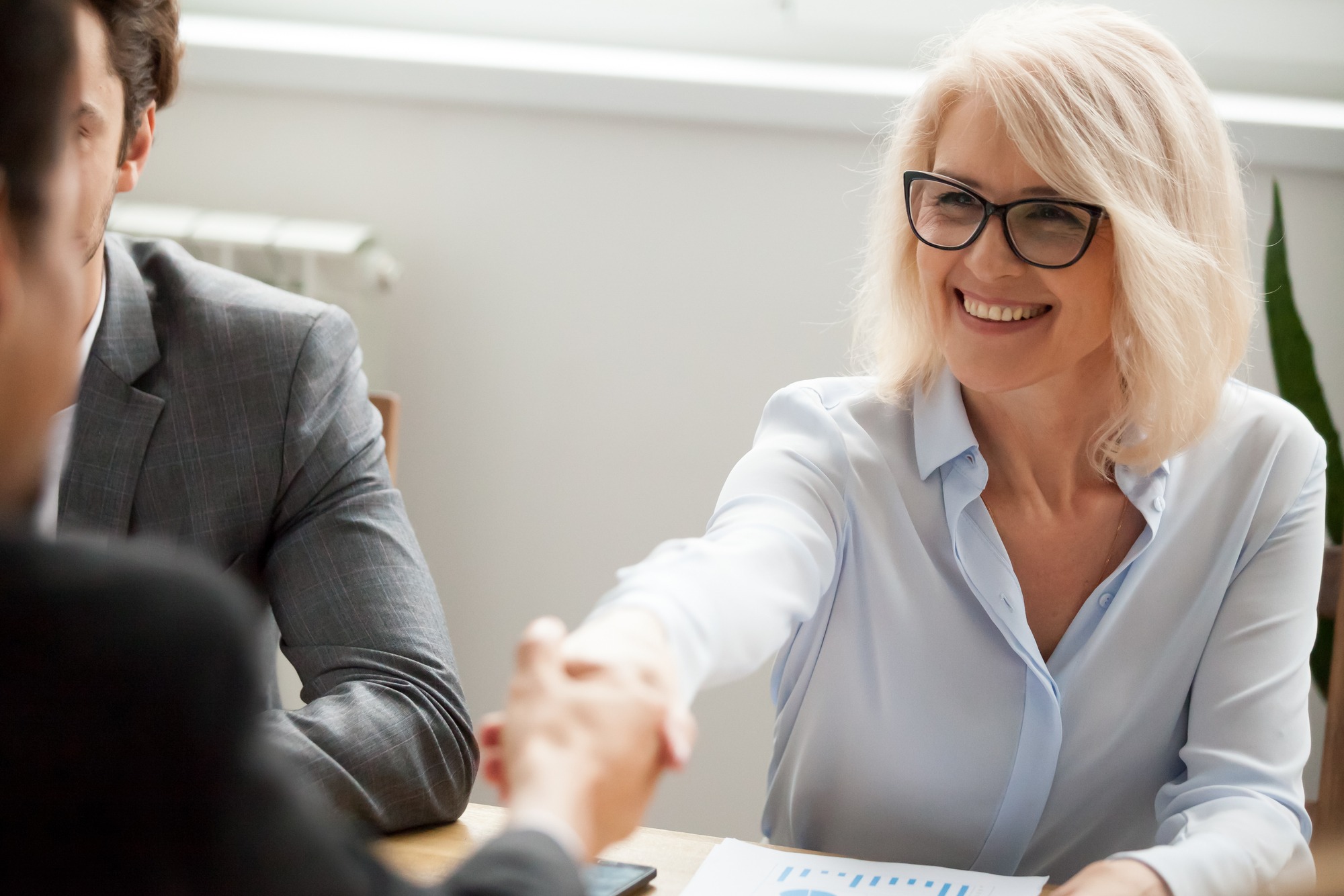 Smiling attractive mature businesswoman handshaking a client