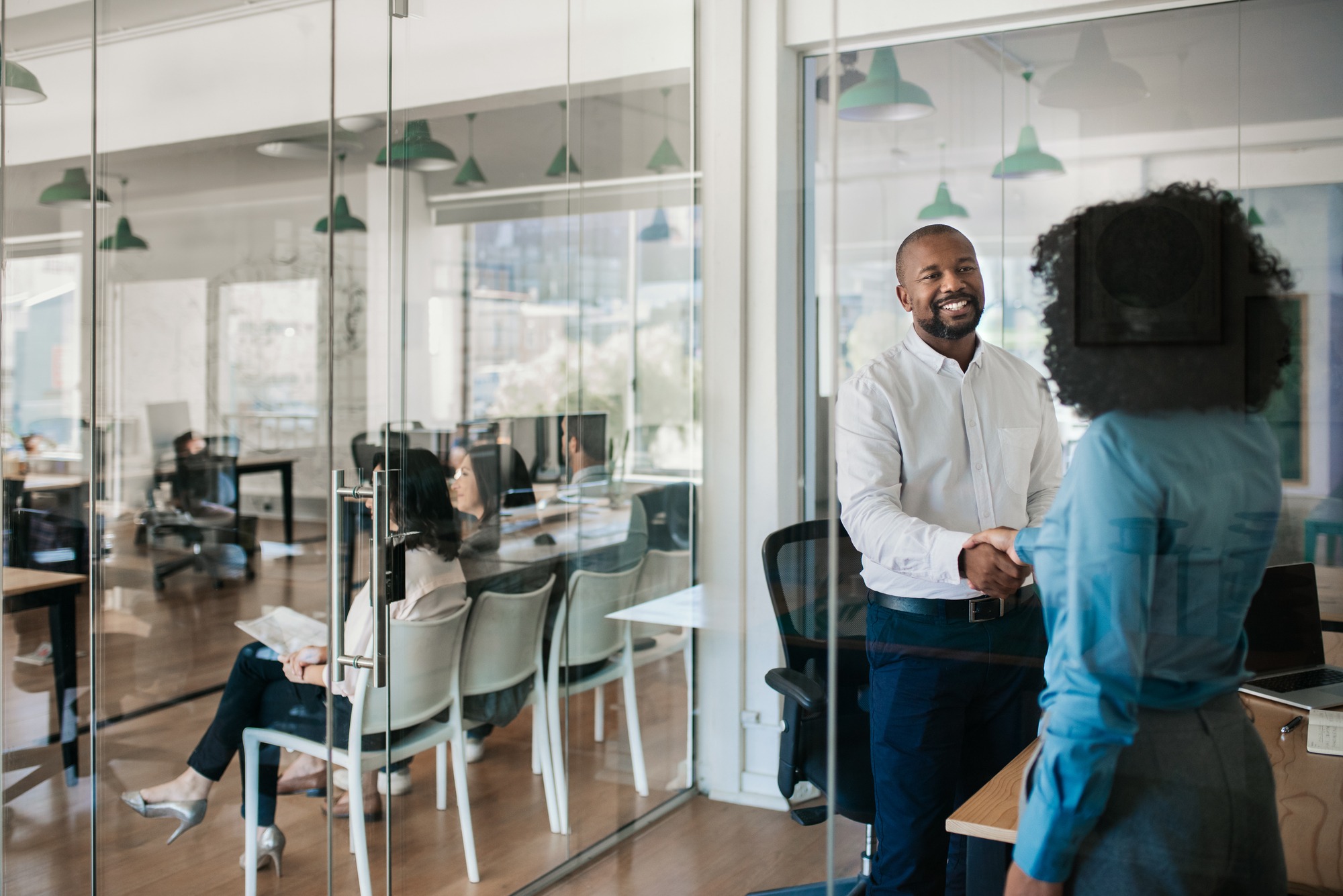 Smiling African American manager standing inside of his office shaking hands